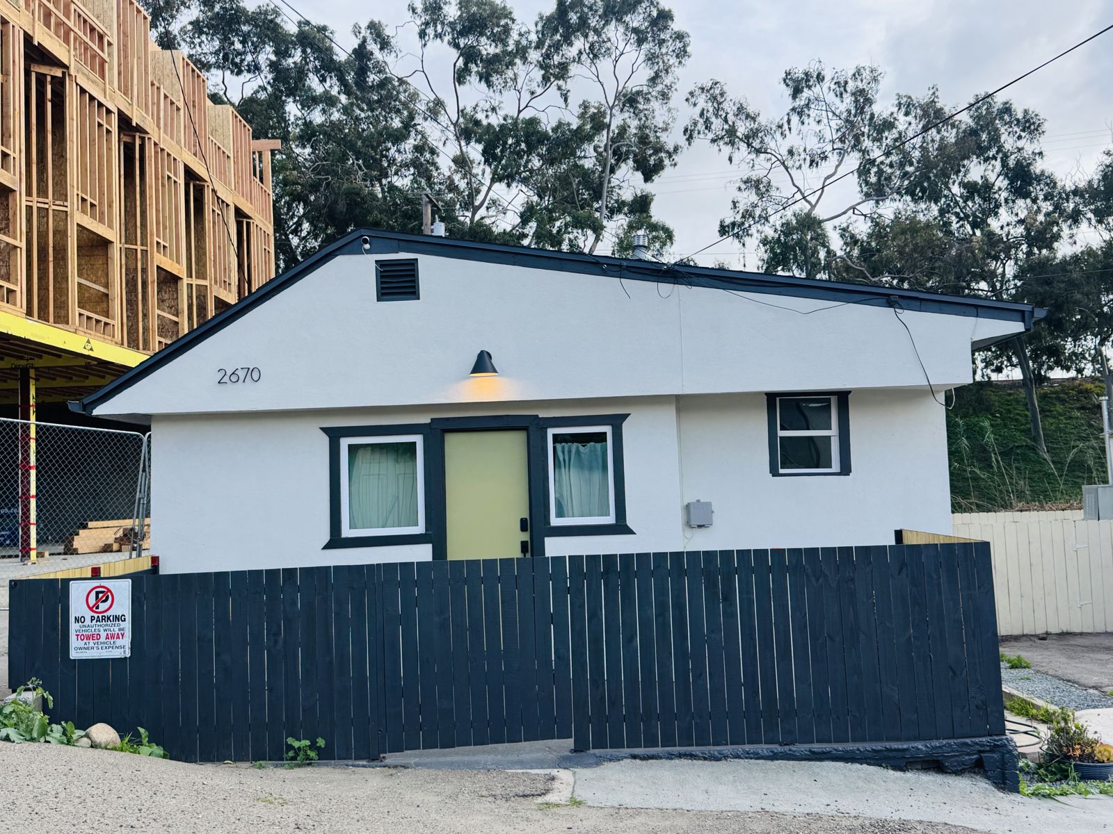 2670 F Street: white house with a yellow door behind a dark wood fence
