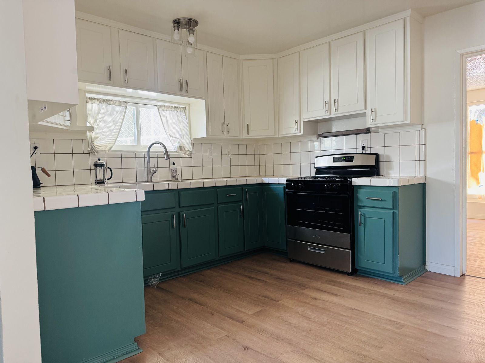 Kitchen with green lower cabinets, white uppers and gas range